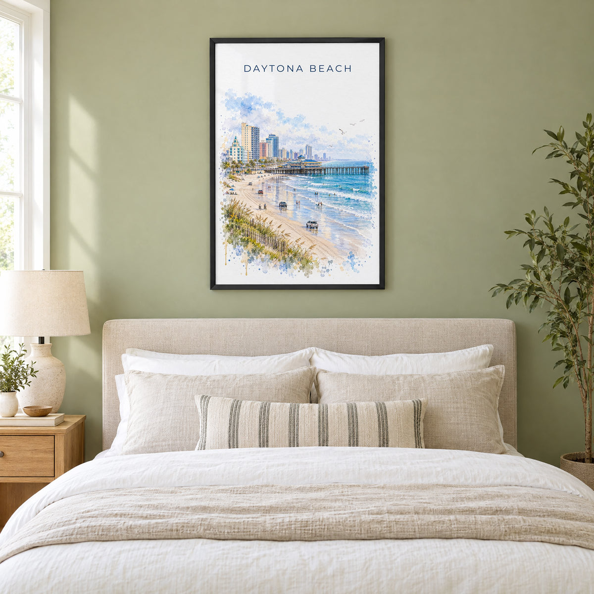 Daytona Beach watercolor print in a black frame above an upholstered headboard in a sage green bedroom