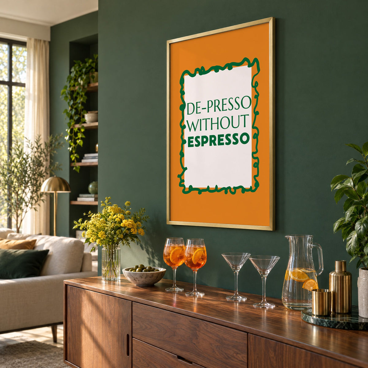 DE-PRESSO WITHOUT ESPRESSO type print in a brass frame on a bottle green wall above a sideboard with spritz and martini glasses, seen at an angle