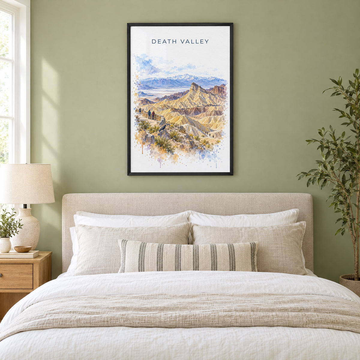 Death Valley National Park watercolor print in a black frame above an upholstered headboard in a sage green bedroom