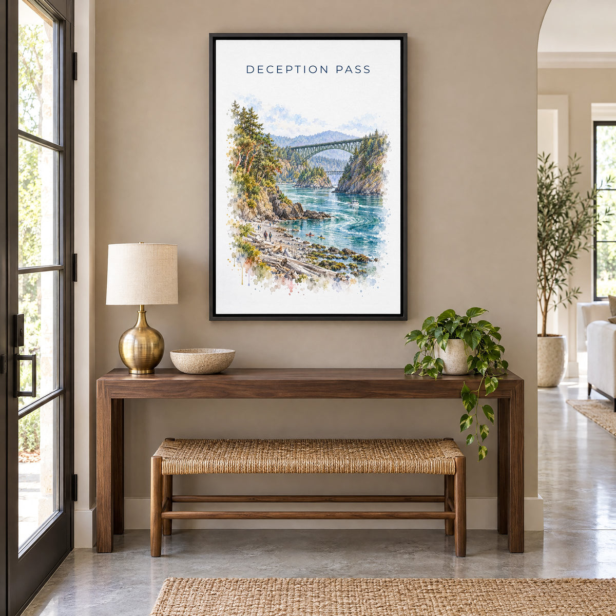 Deception Pass watercolor print as a black floater canvas above a walnut console and woven bench in an entryway