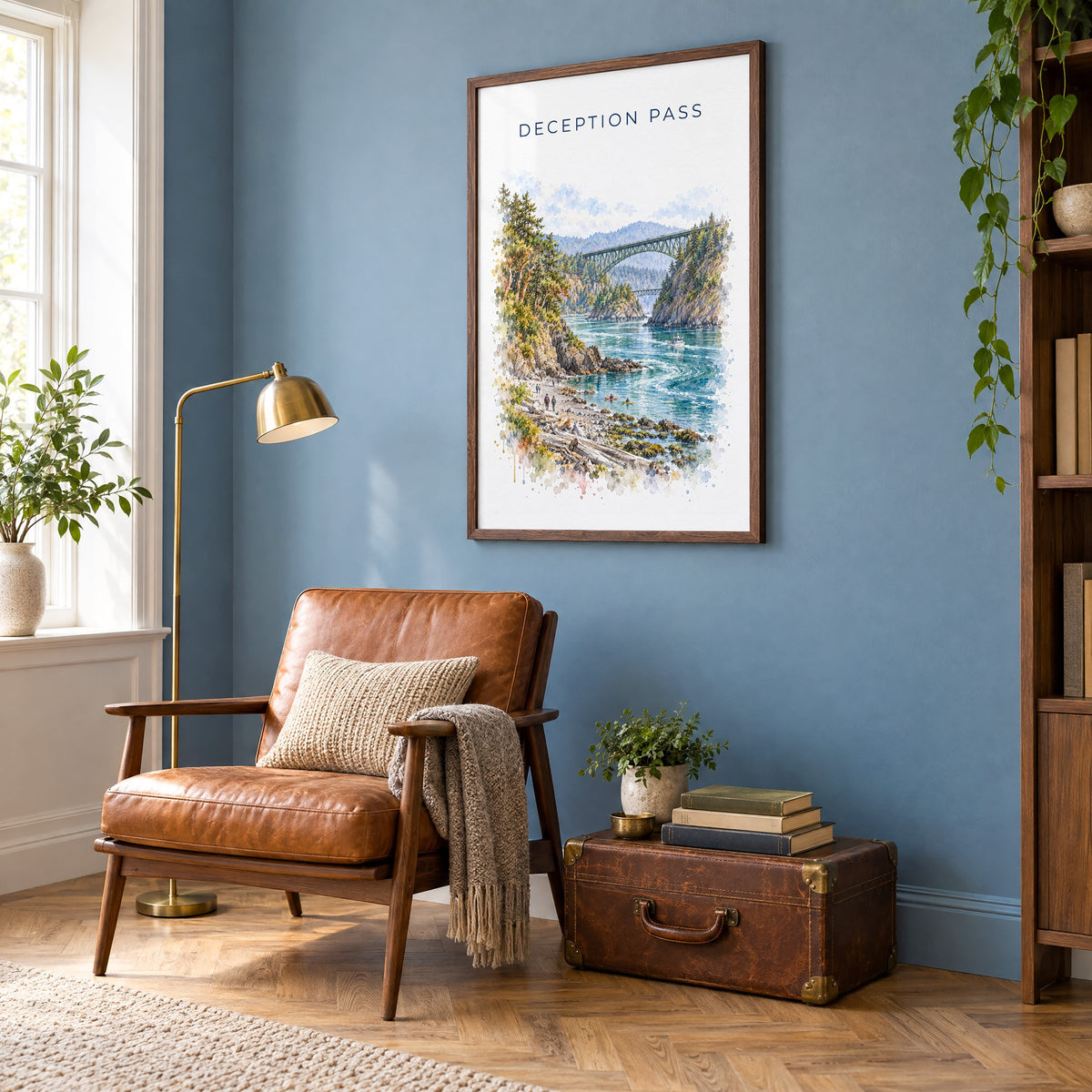 Deception Pass watercolor print in a walnut frame on a blue wall above a leather armchair in a reading nook