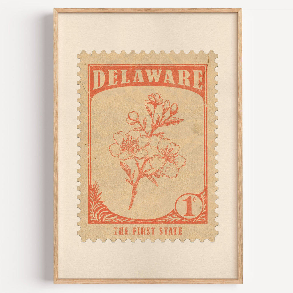 Delaware state flower stamp print in orange red on sand, light oak frame on a plain white wall