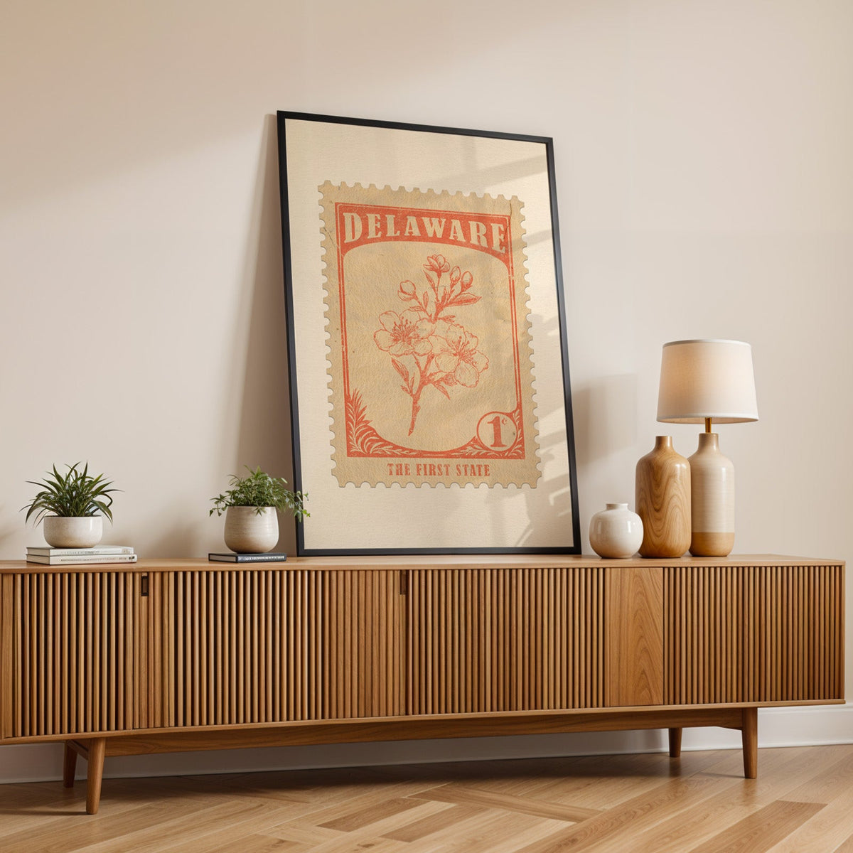 Delaware state flower print in a black frame leaning on a fluted wood credenza with vases and a lamp