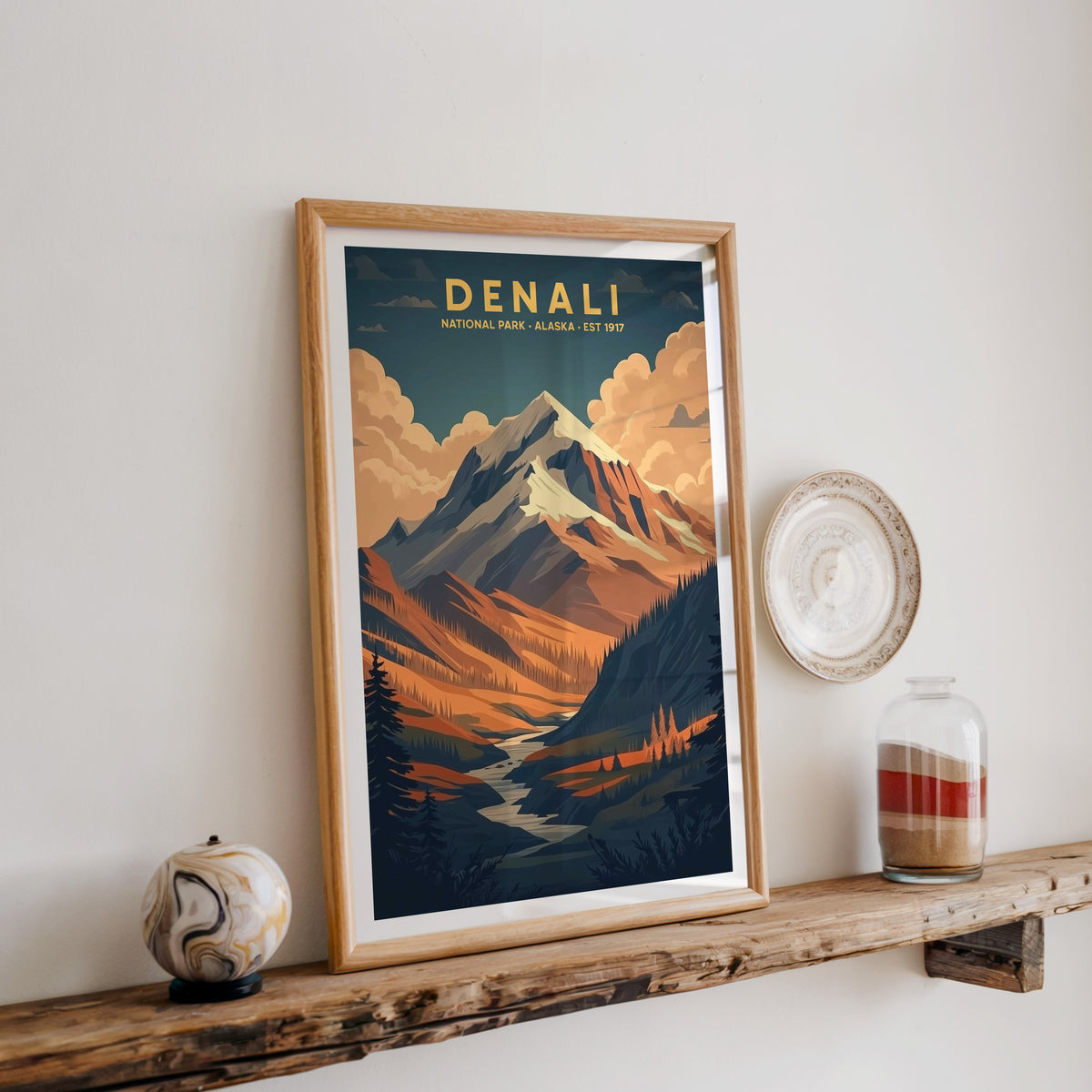 Denali National Park print in an oak frame on a rustic wood shelf with ceramics and a sand jar