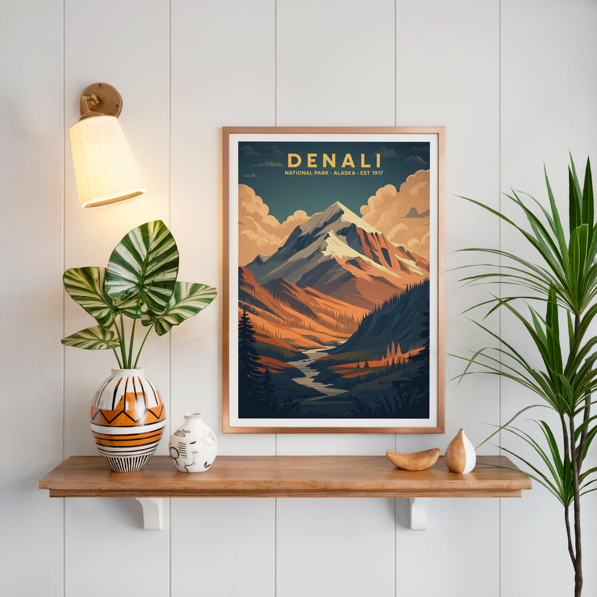 Denali National Park print in a copper frame above an oak shelf on white shiplap with a sconce