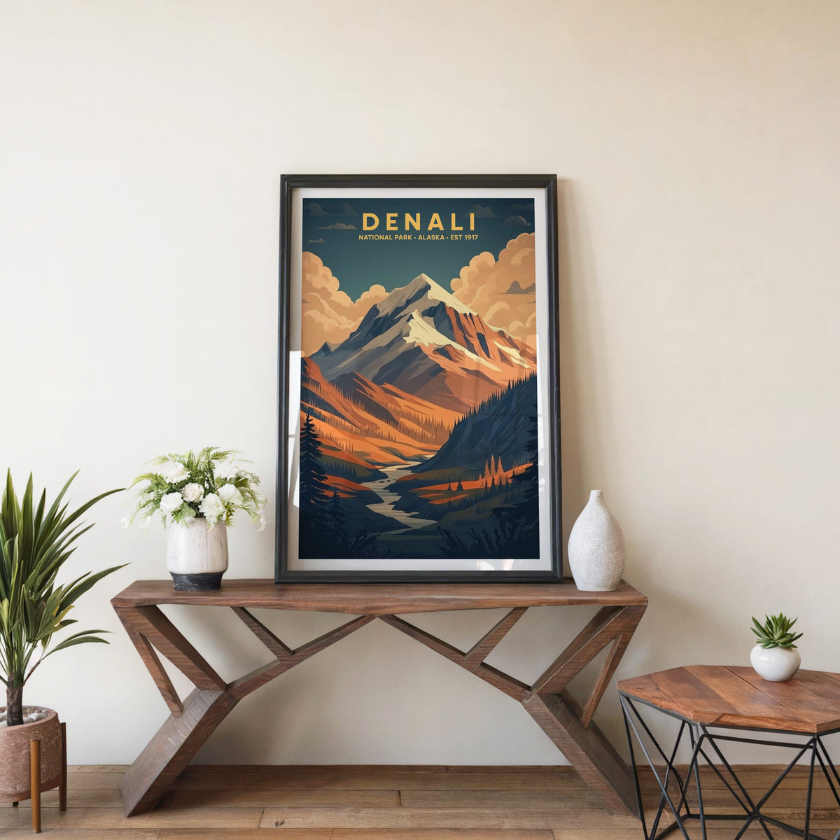 Denali poster in a black frame on an entryway console table beside white flowers and a yucca
