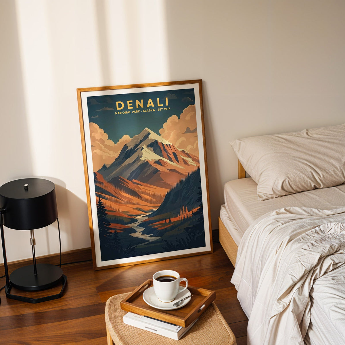 Denali National Park print in an oak frame leaning on a bedroom floor beside the bed and a tray