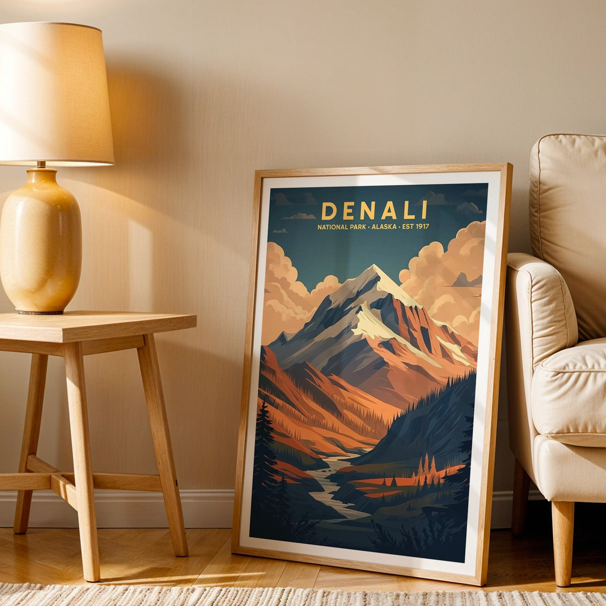Denali print in an oak frame beside a cream armchair and an amber lamp in warm afternoon light