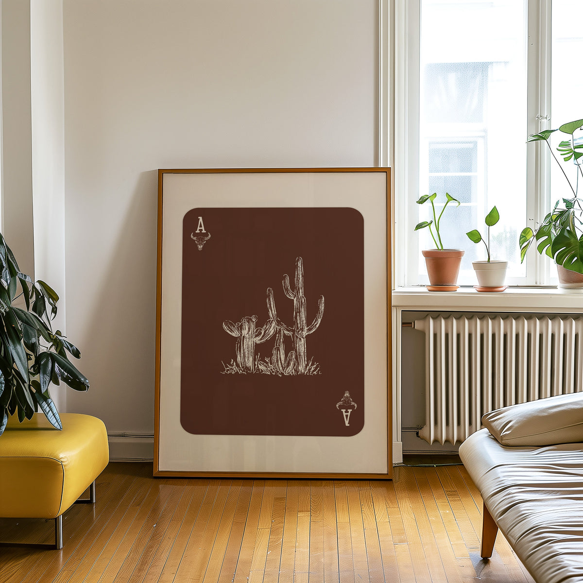Desert cactus card print in an oak frame on a parquet floor beside a yellow bench