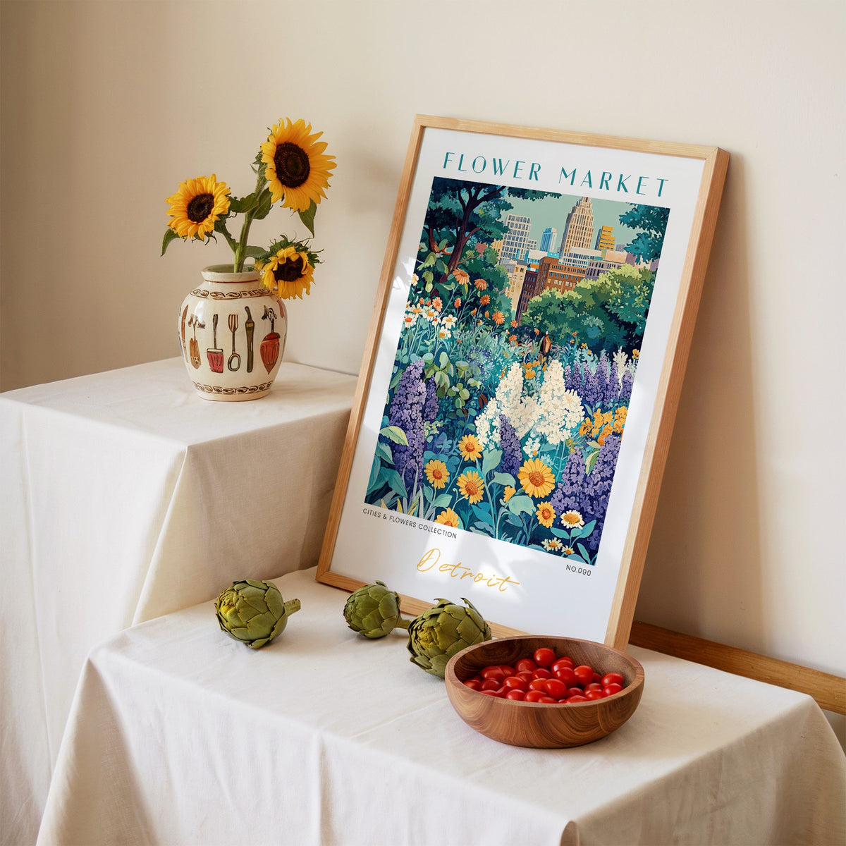 Detroit flower market print in an oak frame leaning on a linen-draped table beside a vase of sunflowers