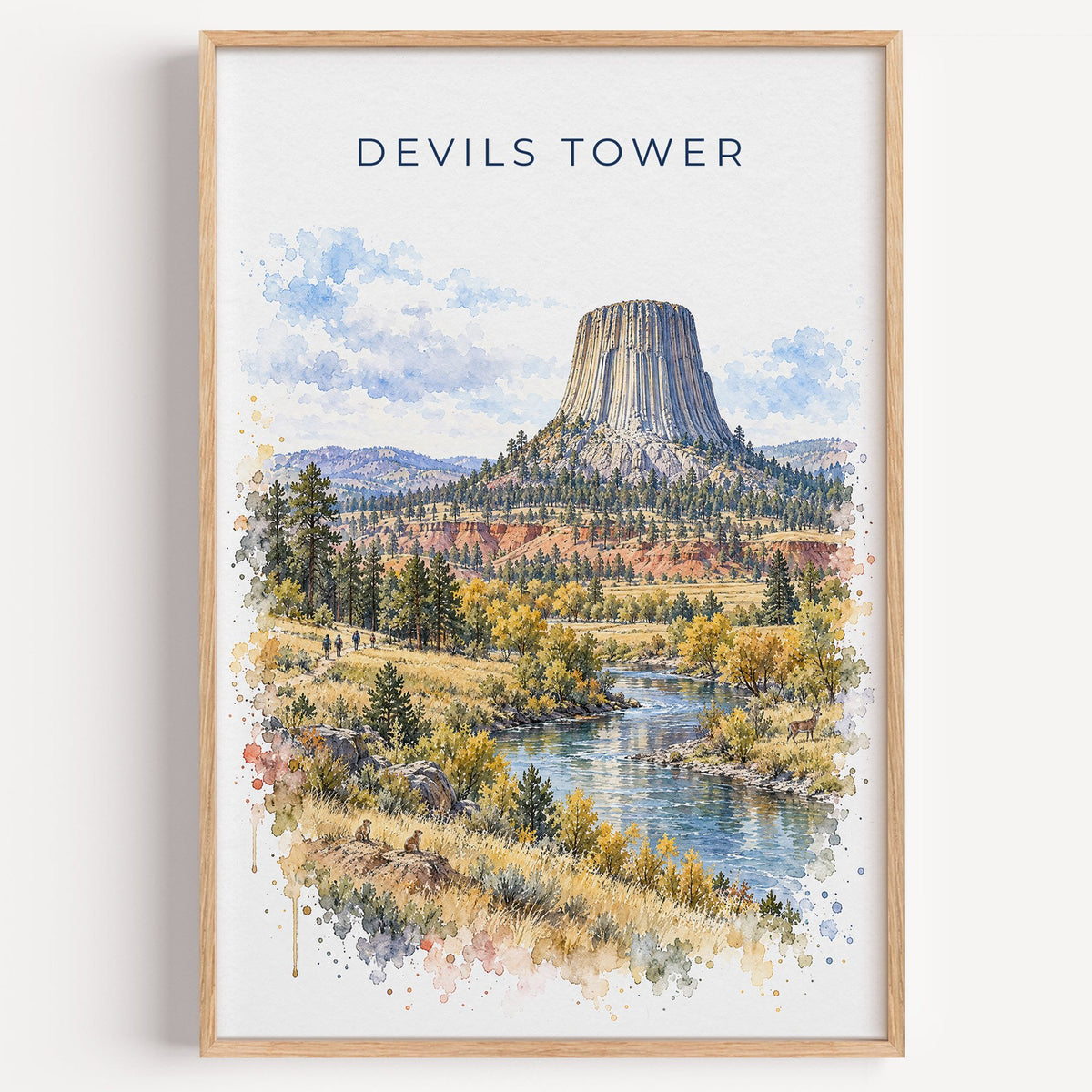 Devils Tower watercolor print in a light oak frame on a plain white wall