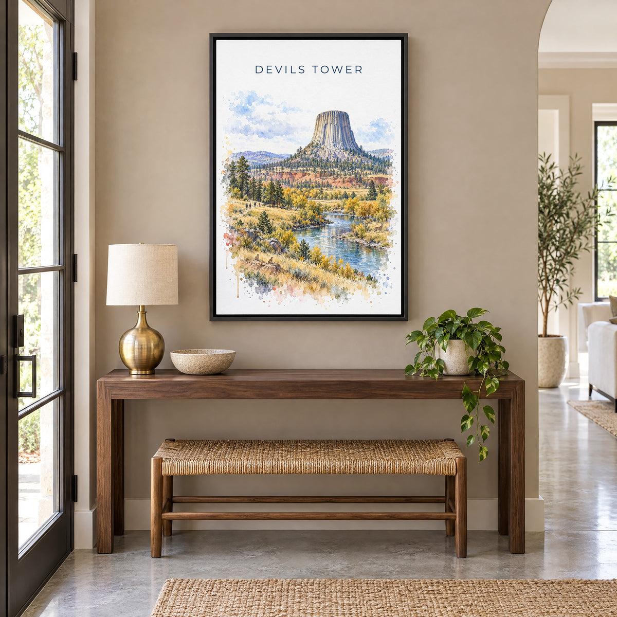 Devils Tower watercolor print as a black floater canvas above a walnut console and woven bench in an entryway