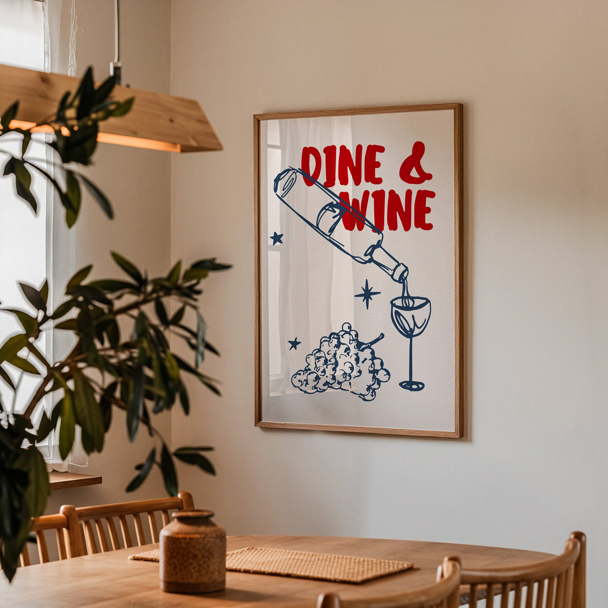 Dine and Wine print in a walnut frame above a dining table with olive branches