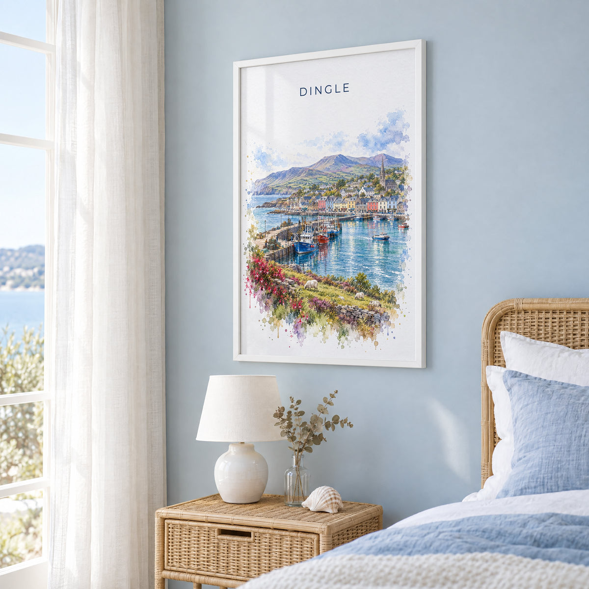 Dingle, Ireland watercolor print in a white frame on a pale blue wall beside a rattan bed in a coastal bedroom