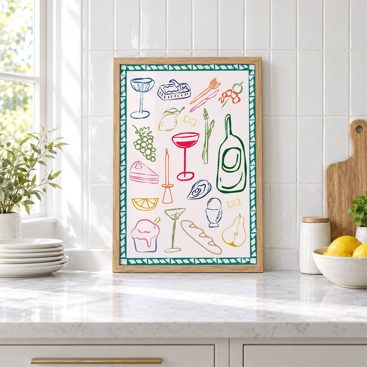 Dinner party doodles teal border print in an oak frame leaning on a marble counter by white tiles and lemons