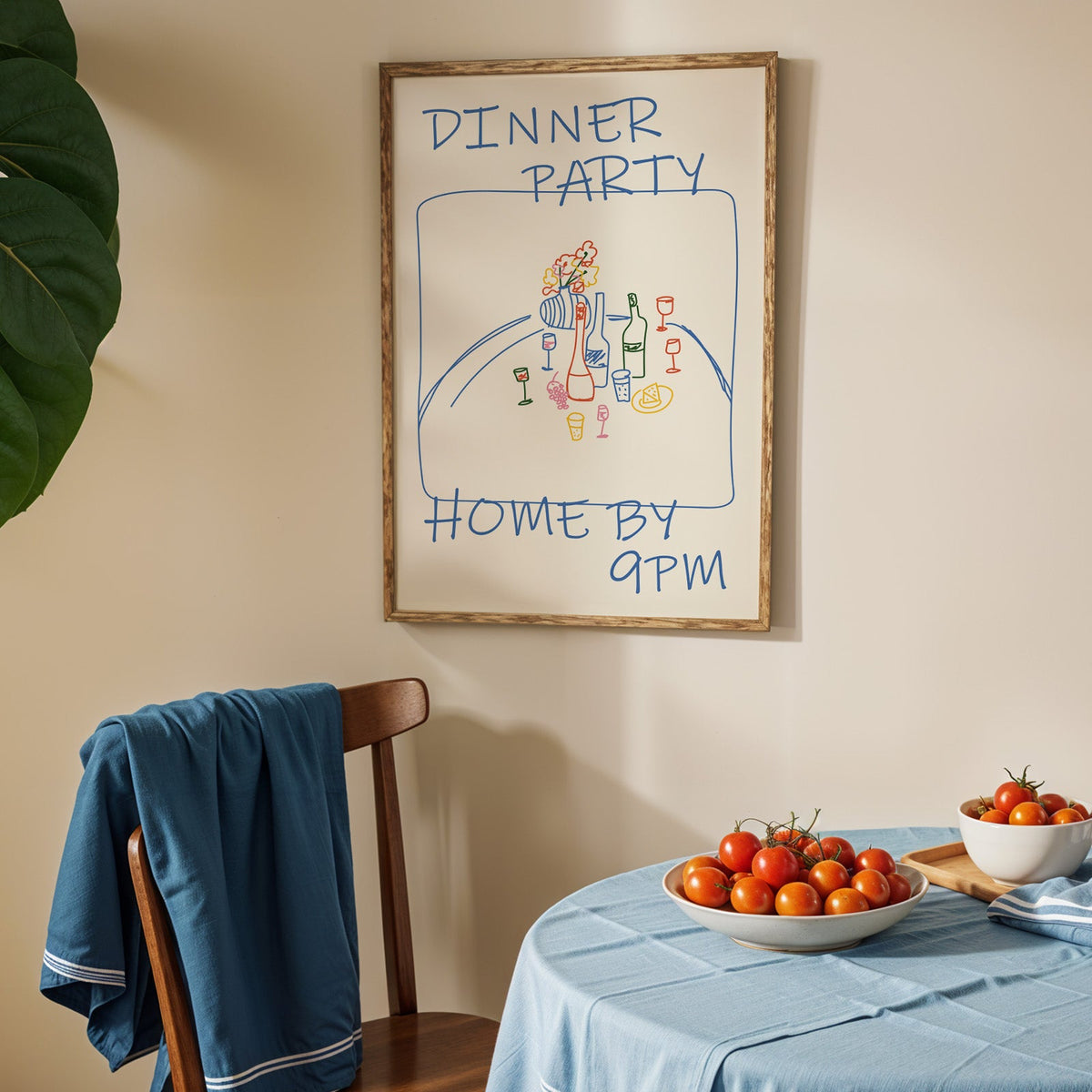 Dinner party blue line print in an oak frame above a blue linen table with ripe tomatoes