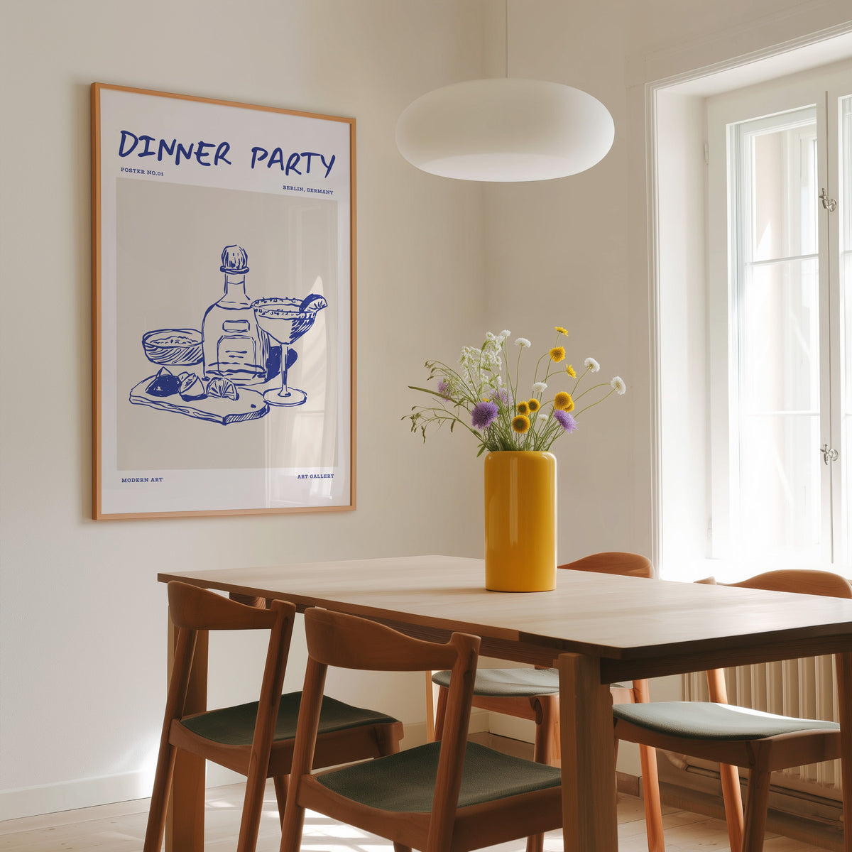 Dinner Party margarita print in a slim oak frame above a dining table