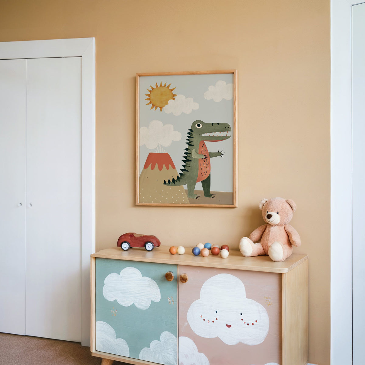 Dinosaur and volcano nursery print in an oak frame on a peach wall above a cloud-painted cabinet