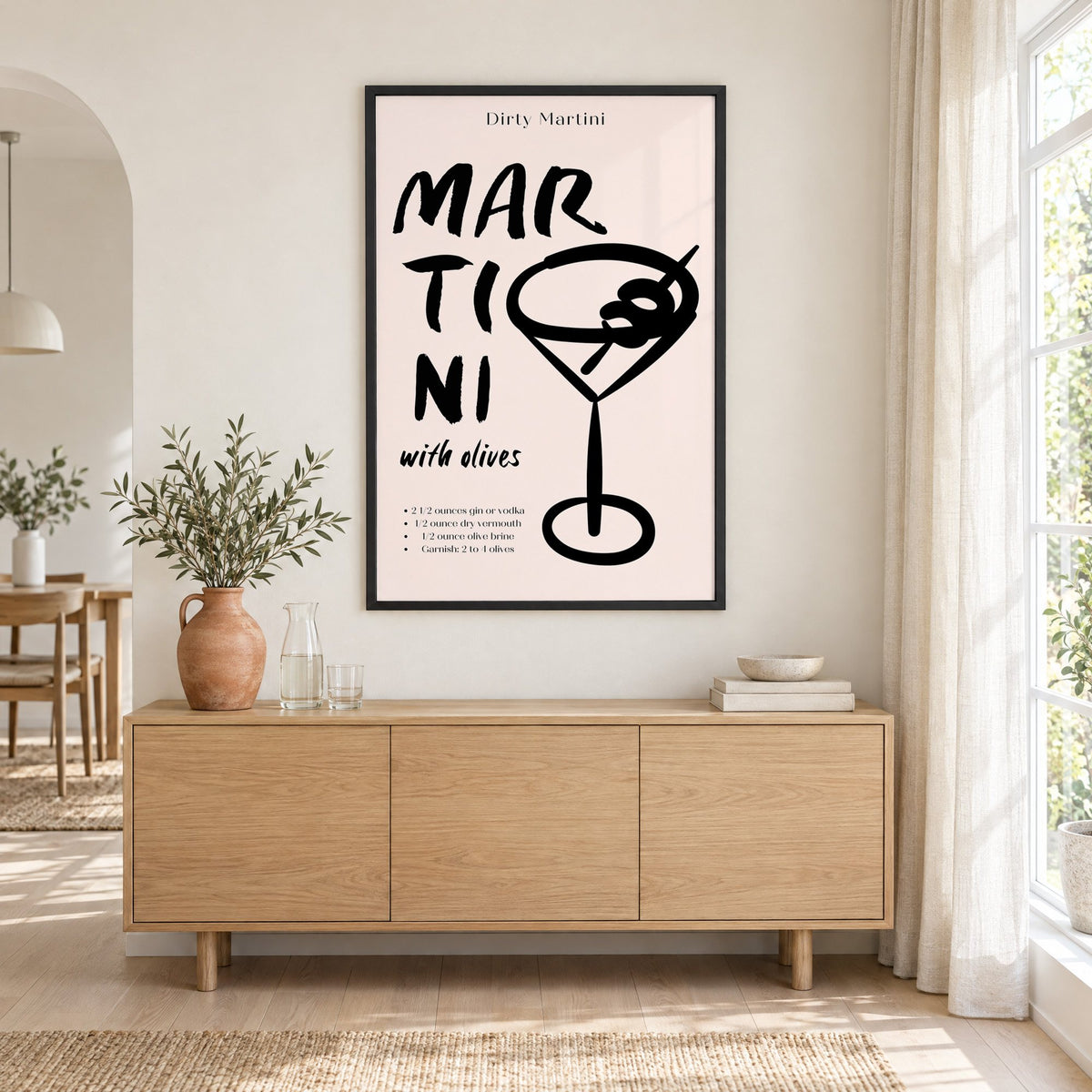 Dirty Martini with olives recipe print in a black frame above an oak sideboard with a terracotta vase of olive branches