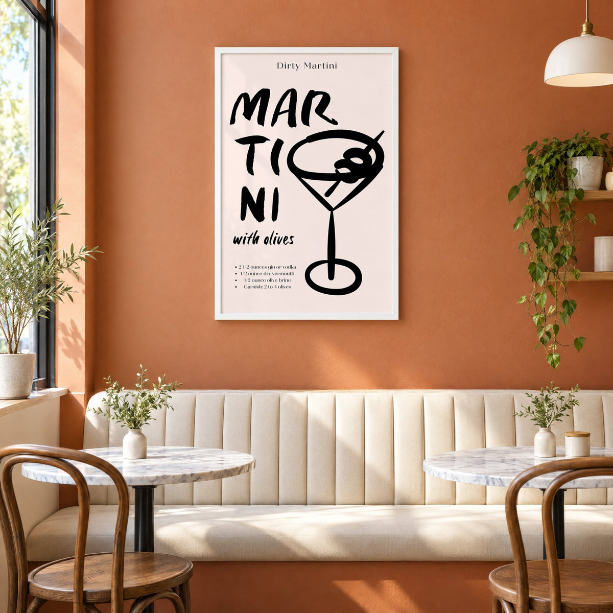 Dirty Martini with olives recipe print in a white frame above a cream banquette on a terracotta cafe wall