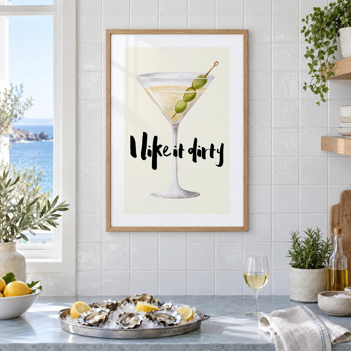 I like it dirty watercolor martini print in an oak frame on white tiles above a marble counter with oysters and lemons by a sea view