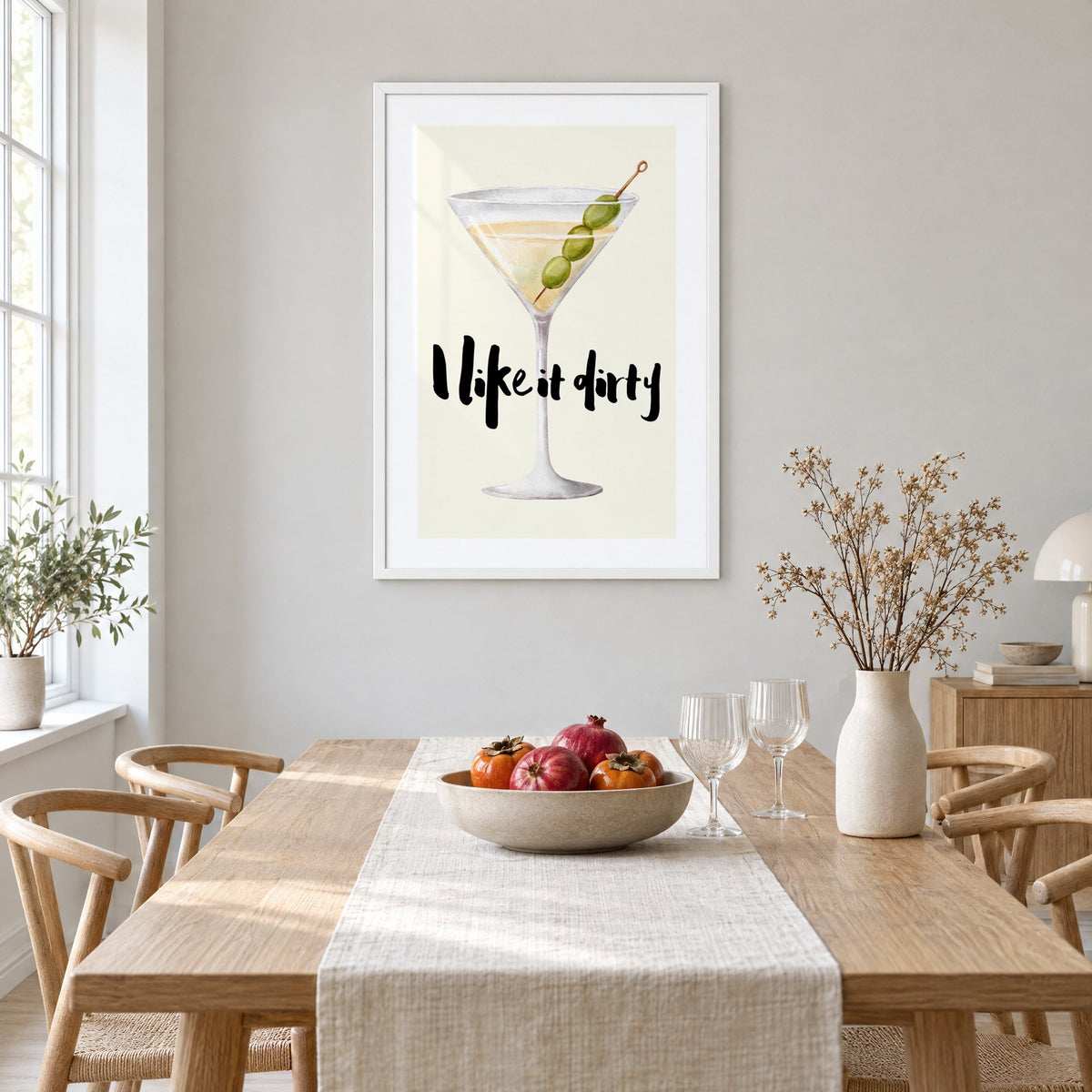I like it dirty watercolor martini print in a white frame above a light oak dining table with a linen runner and fruit bowl