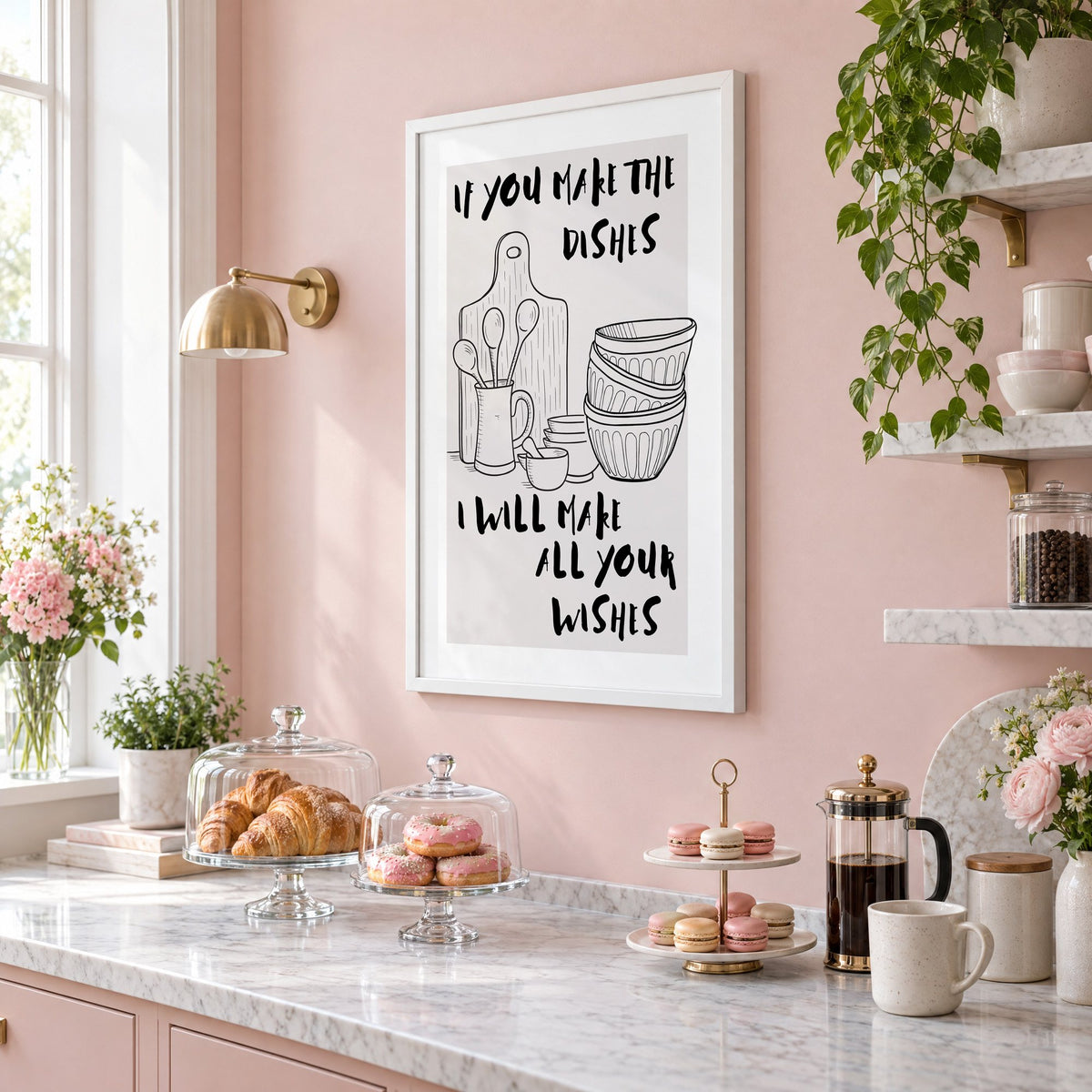 IF YOU MAKE THE DISHES kitchenware sketch print in a white frame on a blush pink wall above a patisserie counter with croissants and macarons, seen at an angle