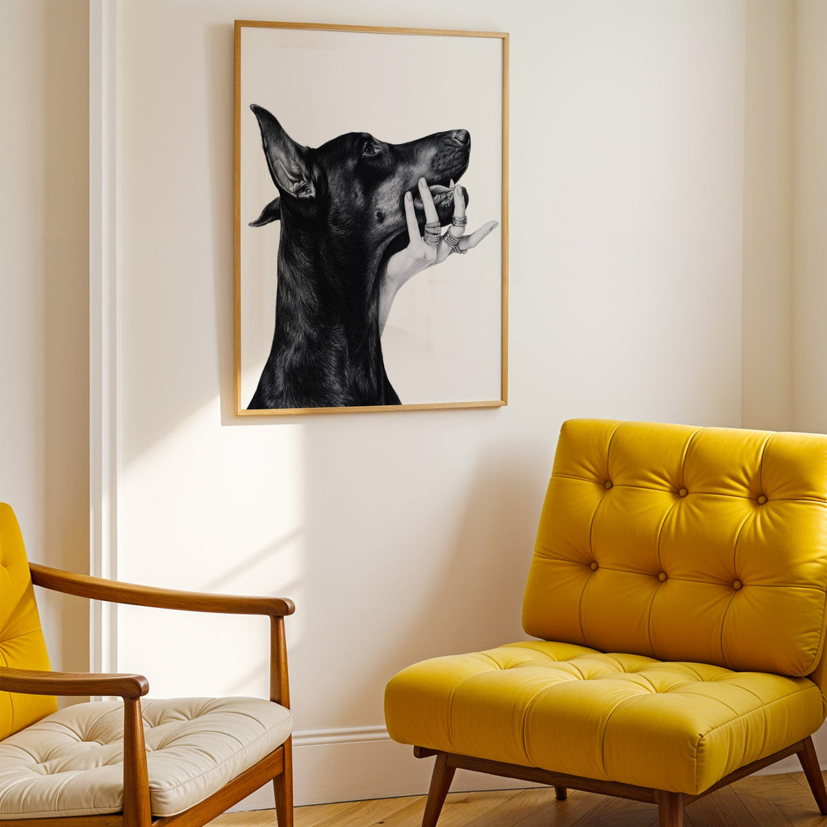 Drawn Doberman with ring-covered hand under chin print shown in a gold frame above a mustard yellow tufted armchair