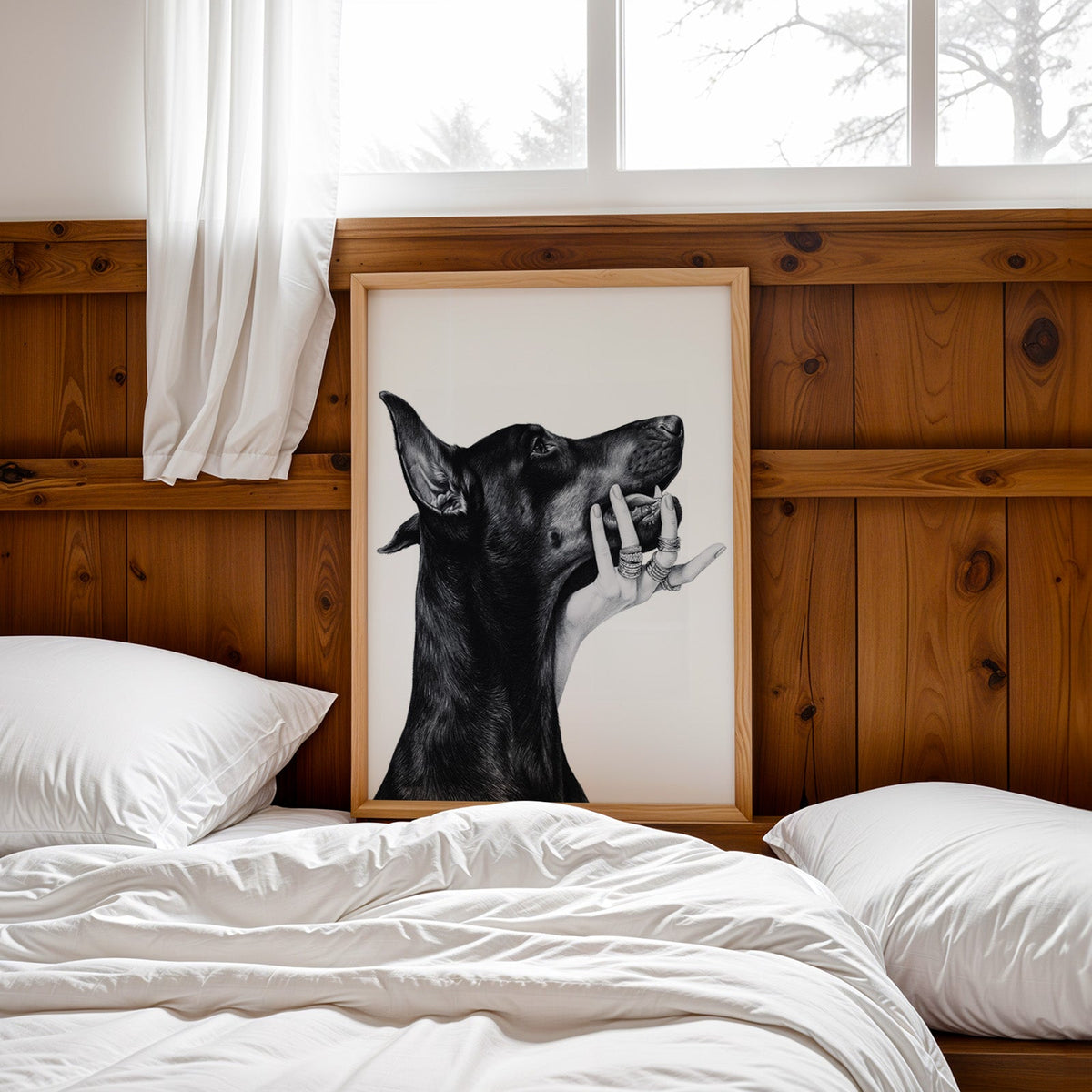Drawn Doberman with ring-covered hand under chin print in a pine frame leaning on a wood headboard over white bedding