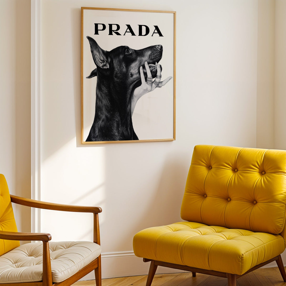 Drawn Doberman with ringed hand under chin print shown in a gold frame above a mustard yellow tufted armchair