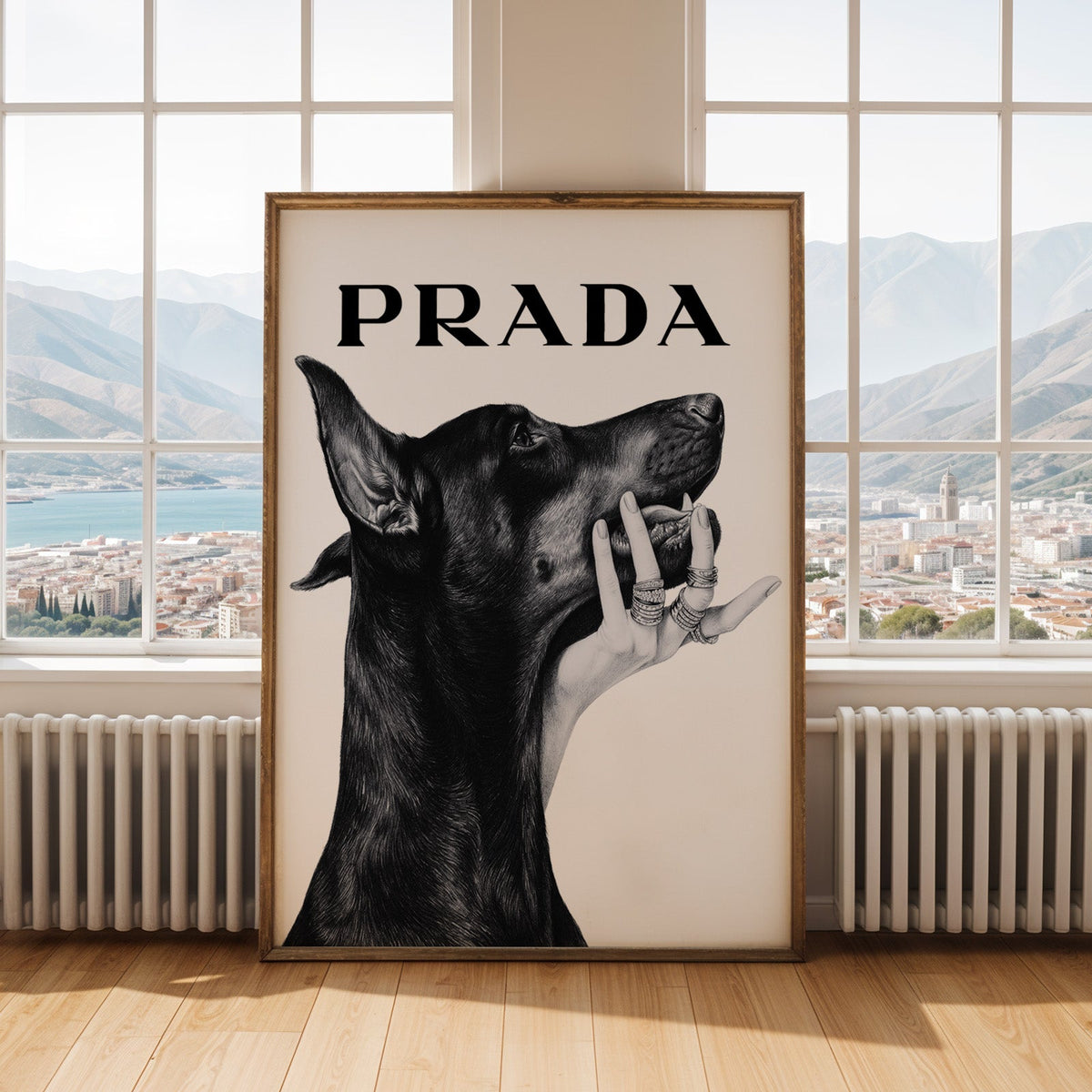Drawn Doberman with ringed hand under chin print shown in an antique gold frame by tall windows with a sea view