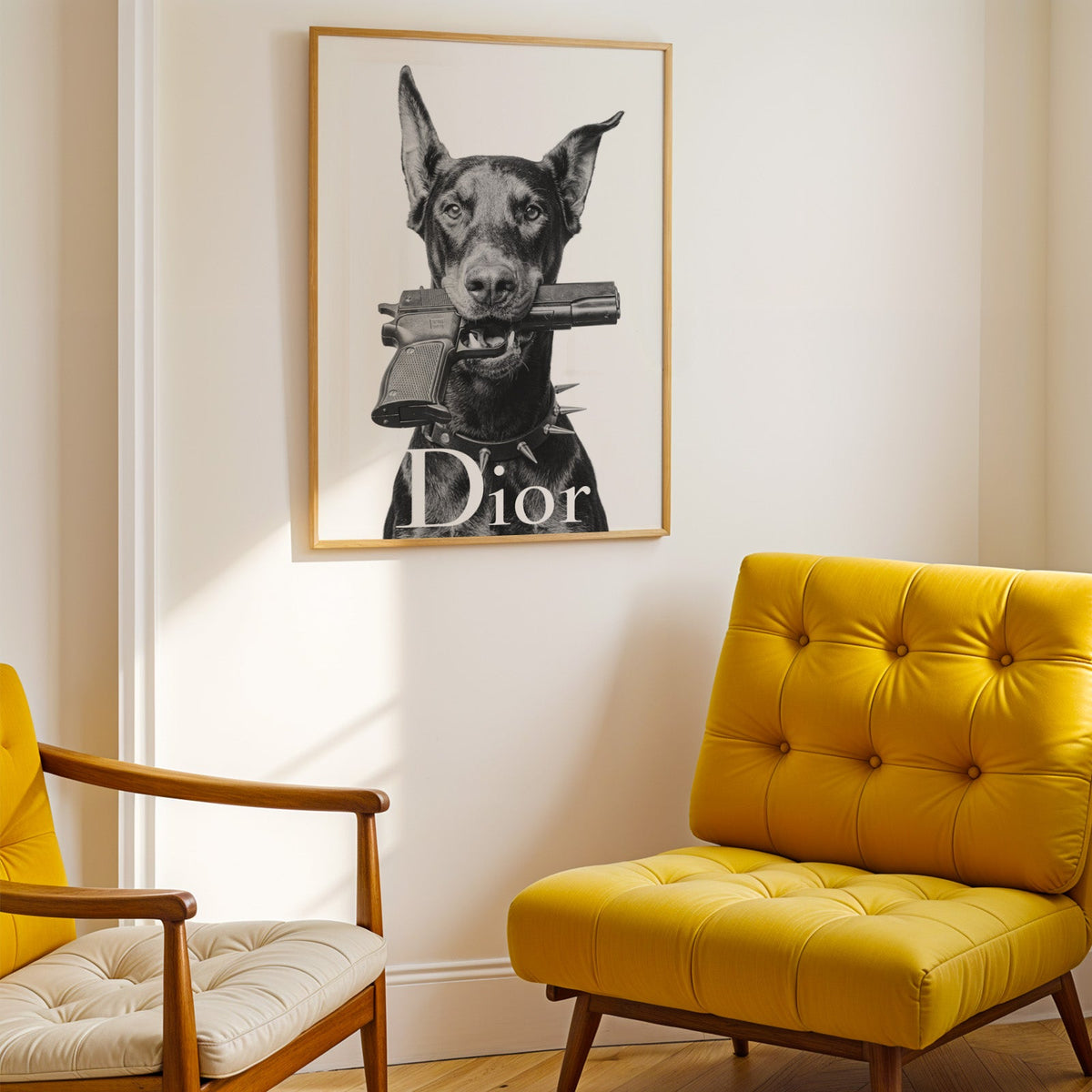Doberman holding toy pistol with white lettering print shown in a gold frame above a mustard yellow tufted armchair