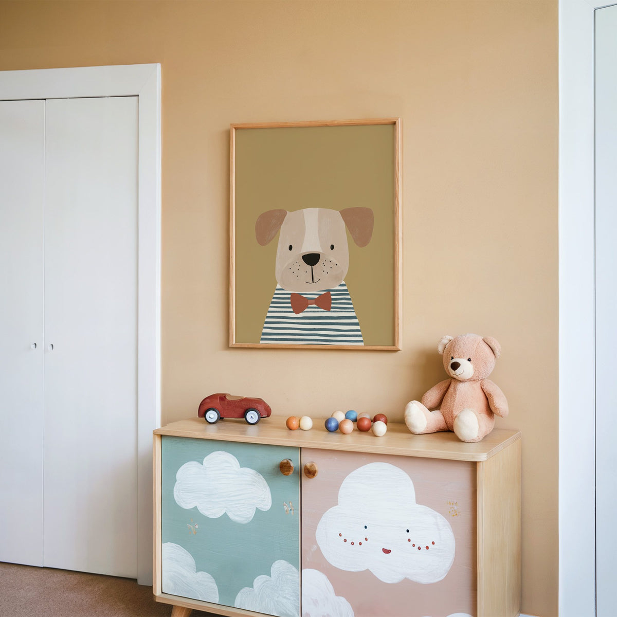 Dog in bow tie portrait nursery print in an oak frame on a peach wall above a cloud-painted cabinet