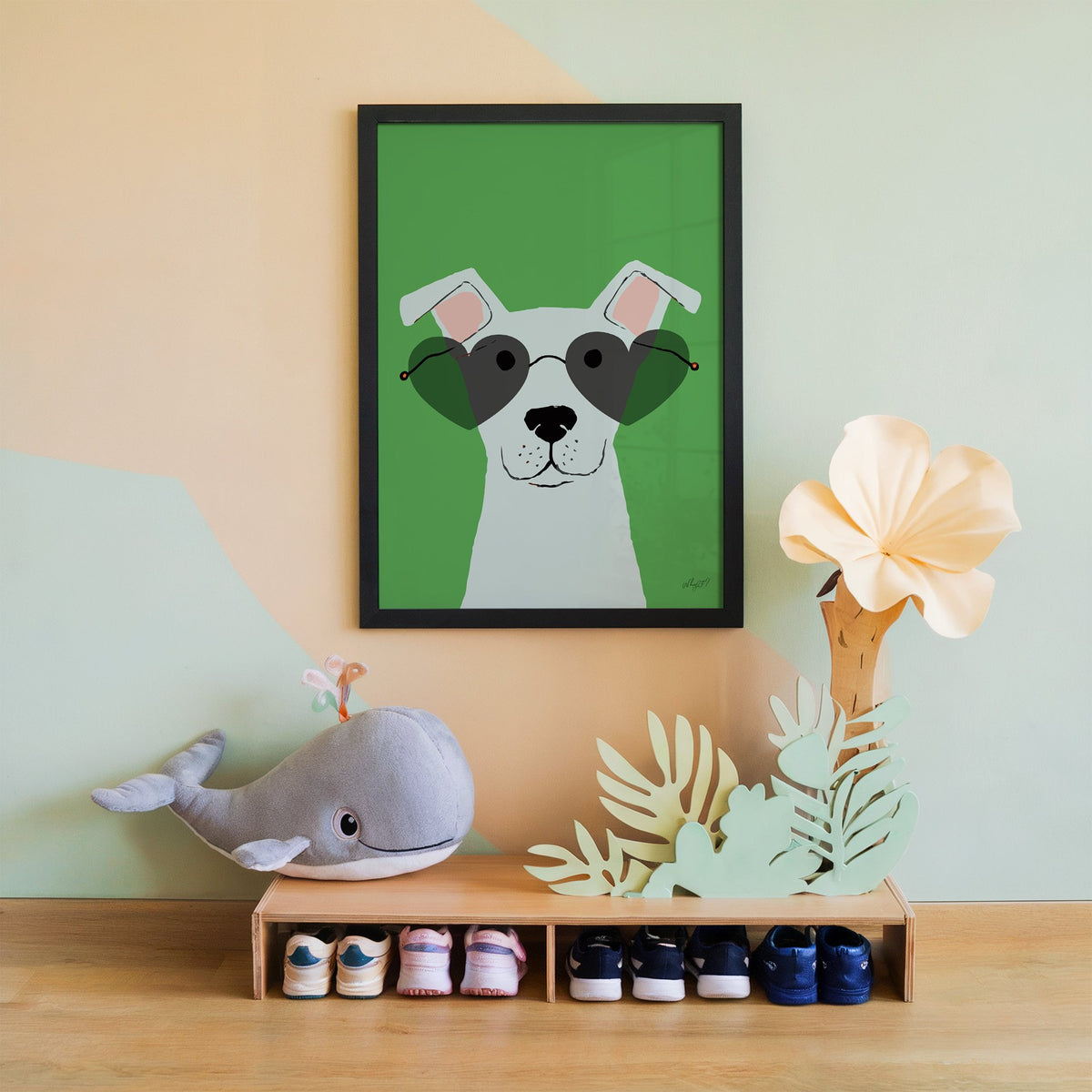 White dog in heart sunglasses nursery print in a black frame on a mint and peach wall above a whale plush