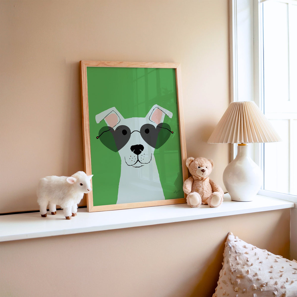 White dog in heart sunglasses nursery print in an oak frame on a window ledge with a toy lamb and teddy