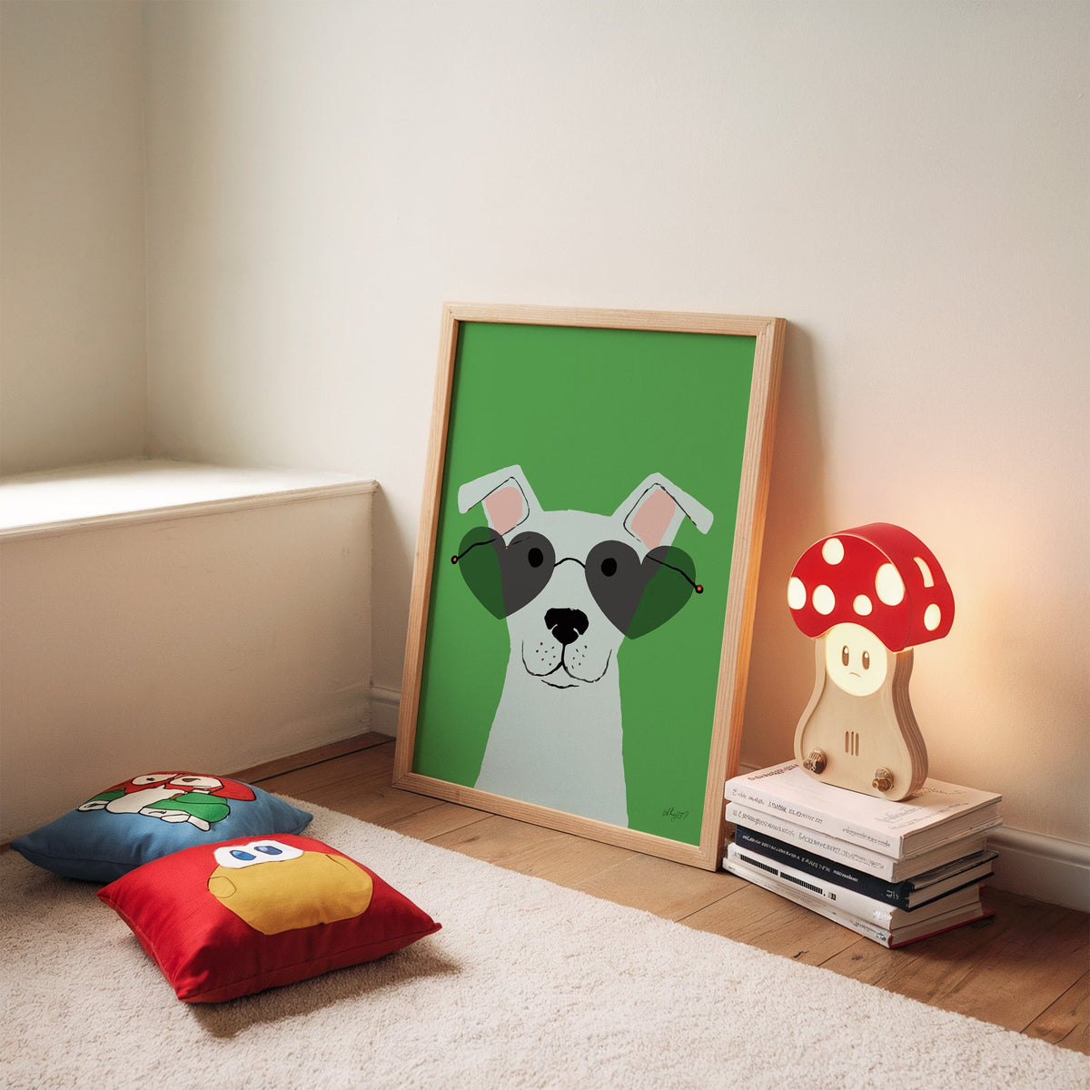 White dog in heart sunglasses nursery print in an oak frame leaning on a rug beside a mushroom lamp and floor cushions