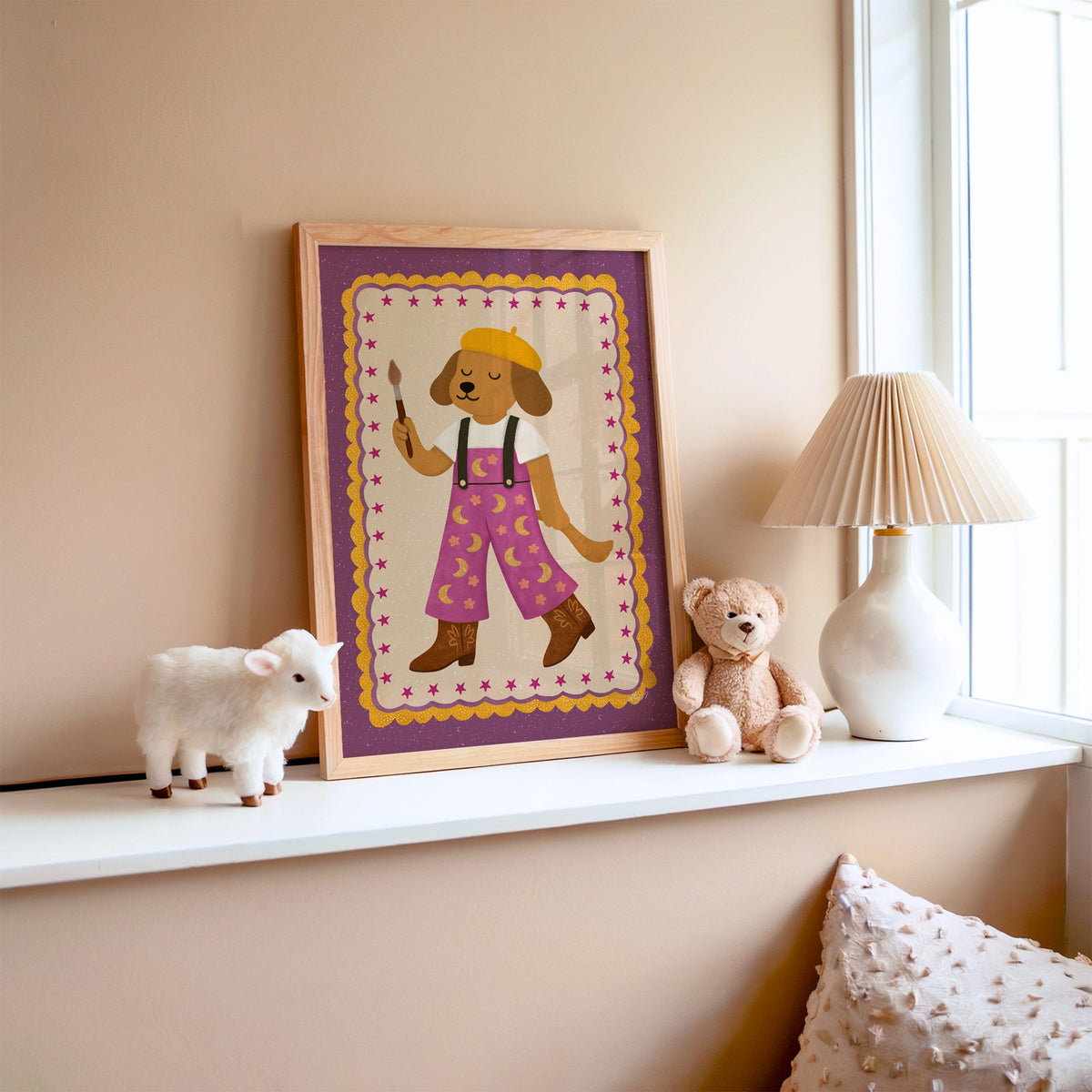 Painter dog in yellow beret nursery print in an oak frame on a window ledge with a toy lamb and teddy