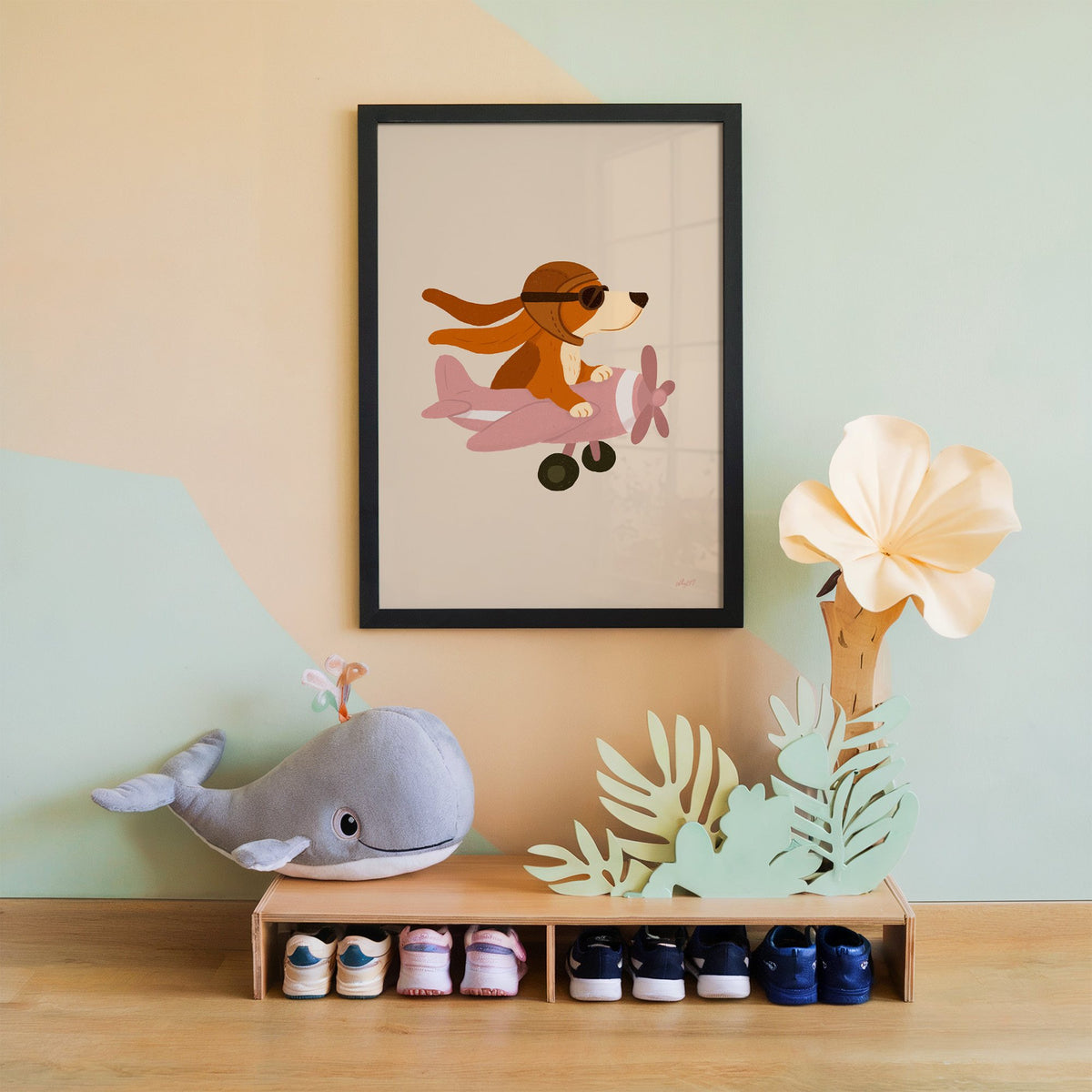 Dog pilot flying pink plane nursery print in a black frame on a mint and peach wall above a whale plush
