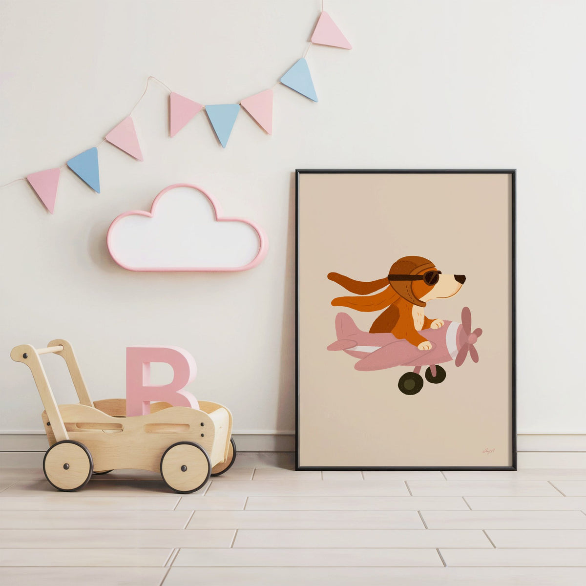 Dog pilot flying pink plane nursery print in a black frame under pastel bunting by a wooden baby walker