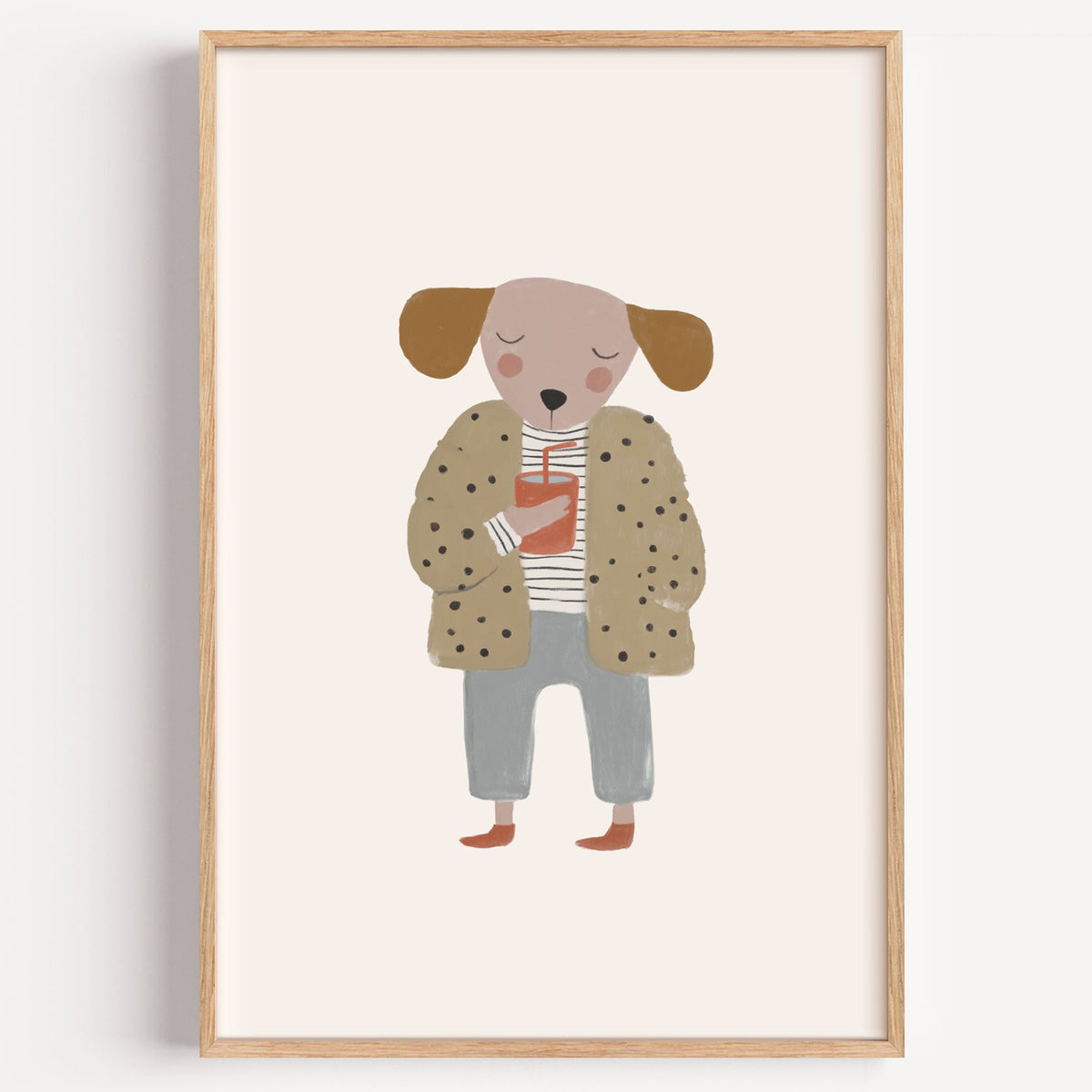 Dog in polka dot coat nursery print in a light oak frame on a plain white wall