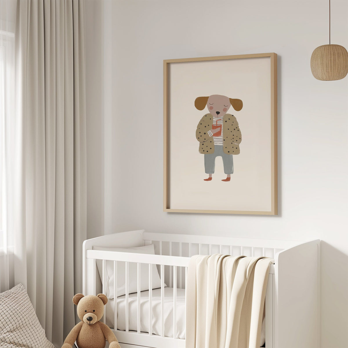 Dog in polka dot coat nursery print in an oak frame above a white crib with a teddy bear