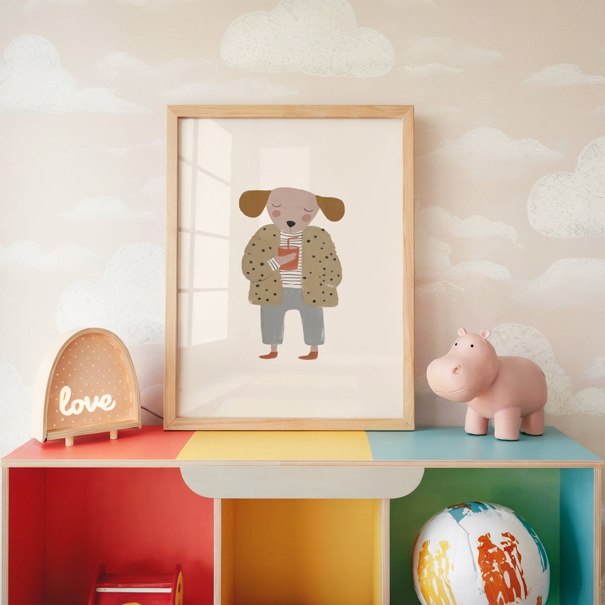 Dog in polka dot coat nursery print in an oak frame on a rainbow toy shelf against cloud wallpaper
