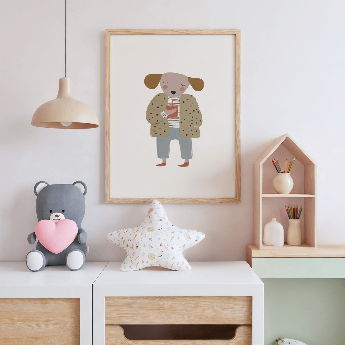 Dog in polka dot coat nursery print in an oak frame above a white dresser with a star pillow and house shelf