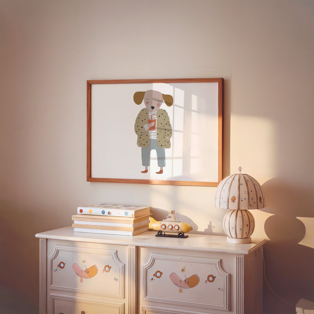 Landscape dog in polka dot coat nursery print in a cherry wood frame above a painted dresser and lamp