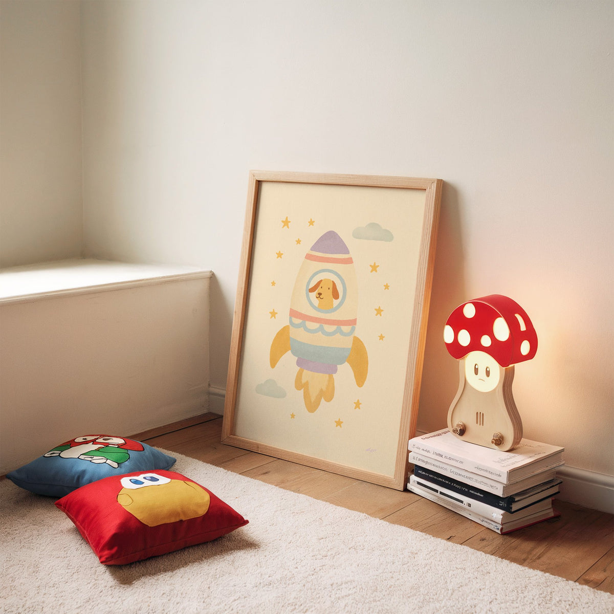 Smiling dog in pastel rocket nursery print in an oak frame leaning on a rug beside a mushroom lamp and floor cushions