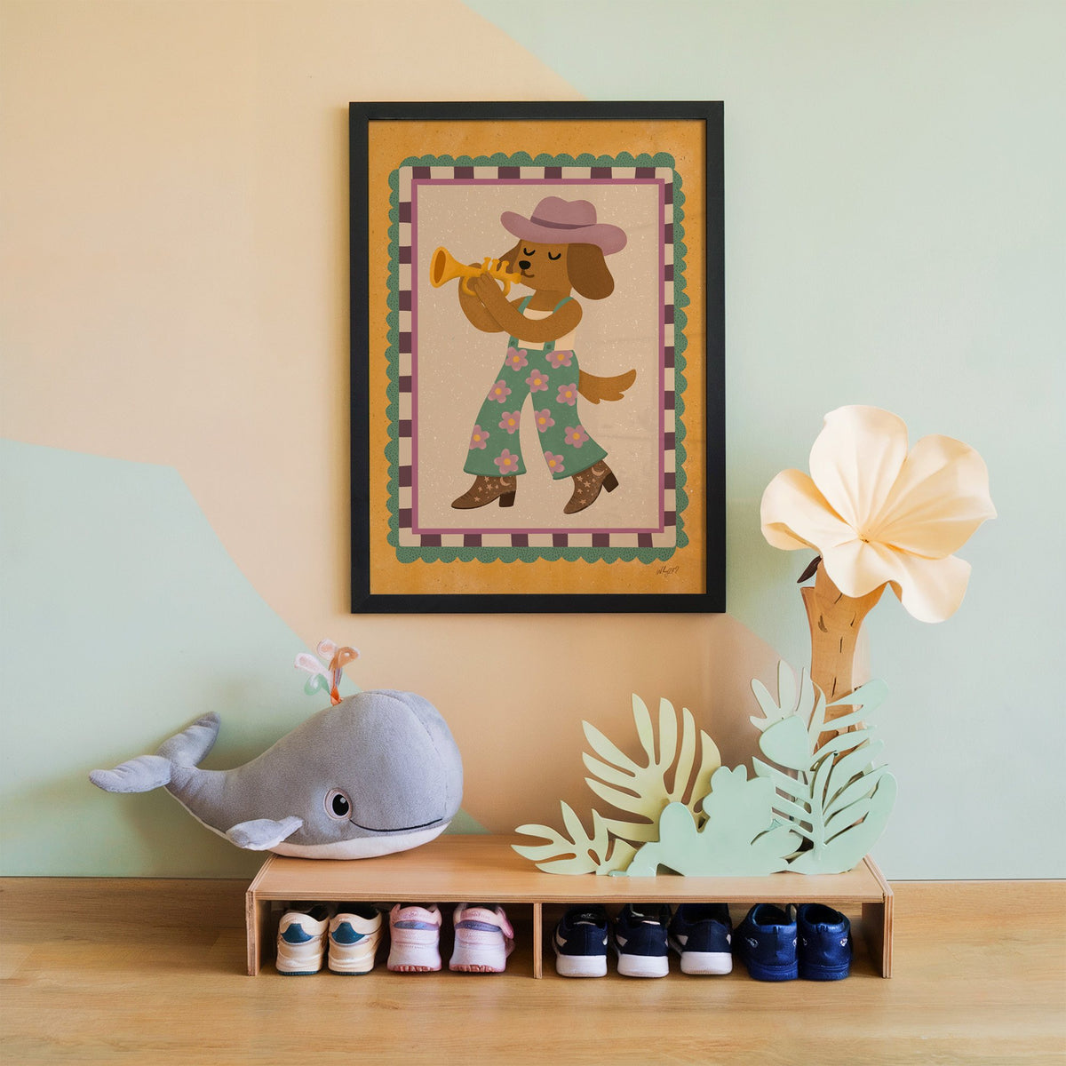Dog playing trumpet in cowboy hat nursery print in a black frame on a mint and peach wall above a whale plush