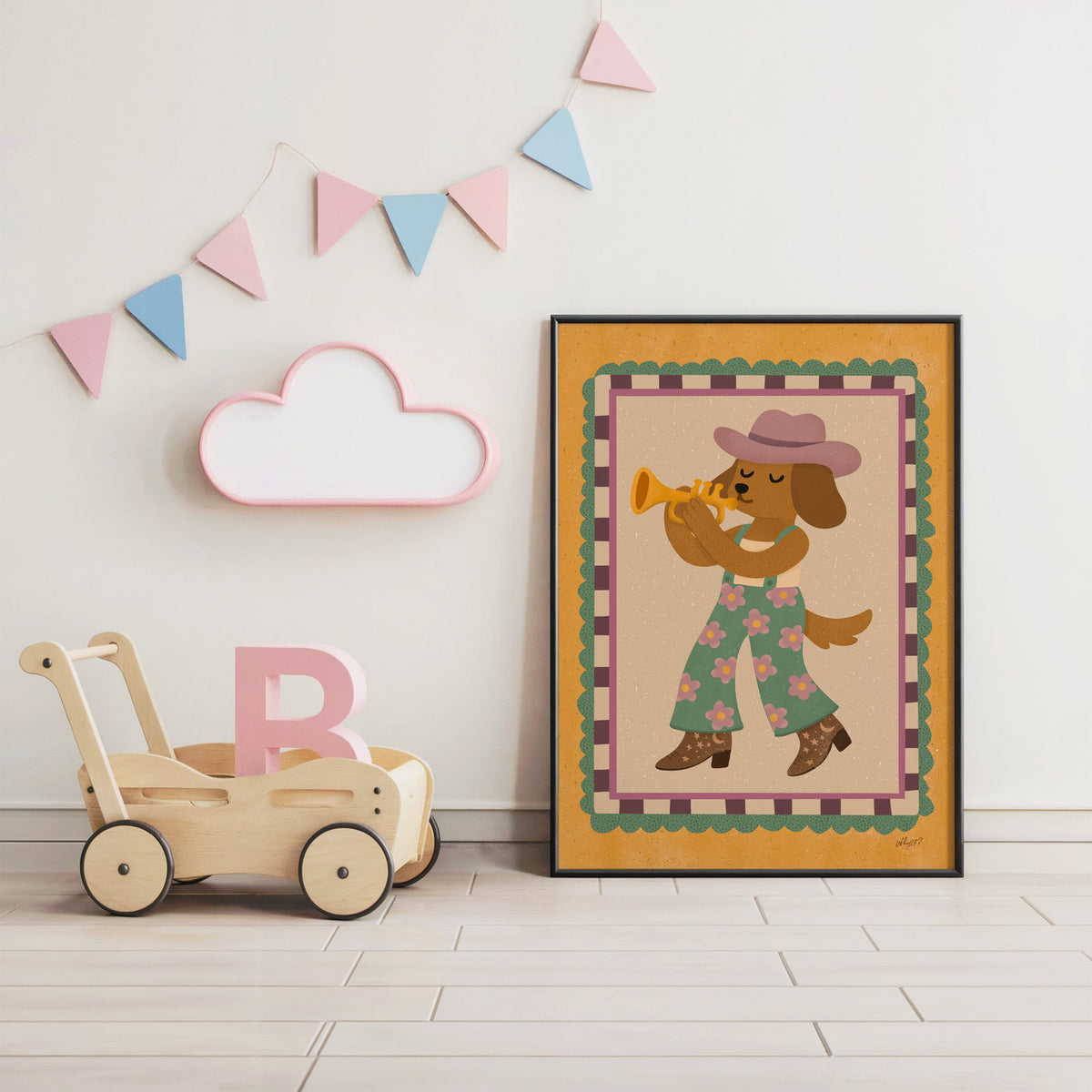 Dog playing trumpet in cowboy hat nursery print in a black frame under pastel bunting by a wooden baby walker