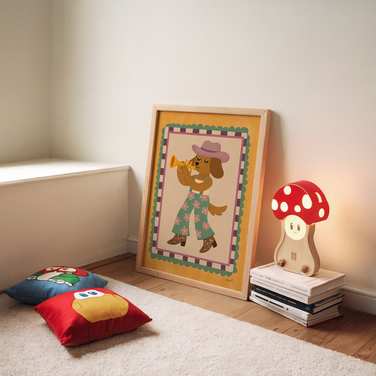 Dog playing trumpet in cowboy hat nursery print in an oak frame leaning on a rug beside a mushroom lamp and floor cushions