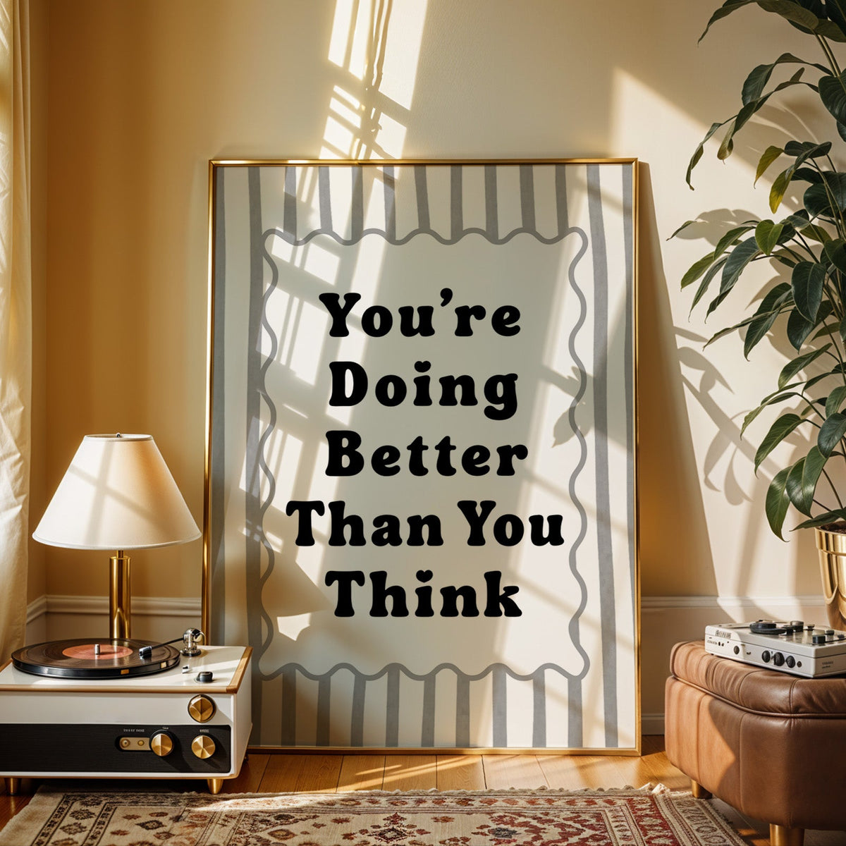 You're doing better than you think striped quote print shown in a gold frame beside a record player and table lamp