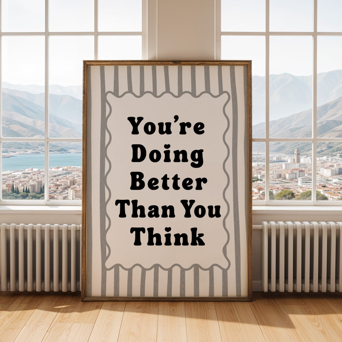 You're doing better than you think striped quote print shown in an antique gold frame by tall windows with a sea view